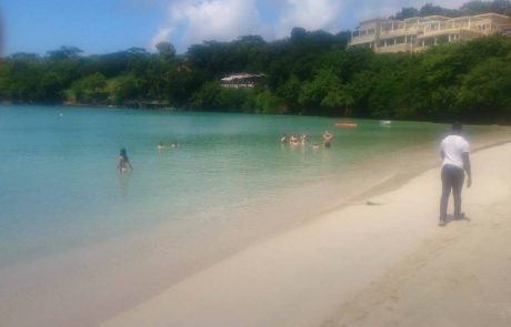 Badegäste am ruhigen Strand vor bewaldeten Hügeln