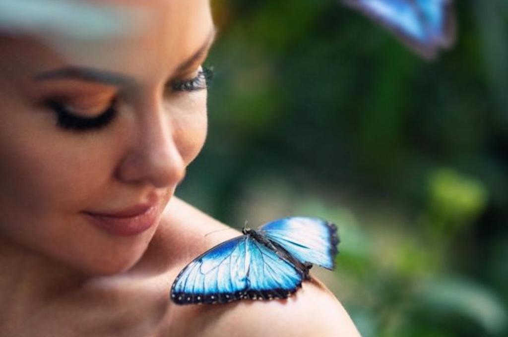 Frau mit Schmeterling Blauer Morphofalter sitzt auf der Schulter einer Frau