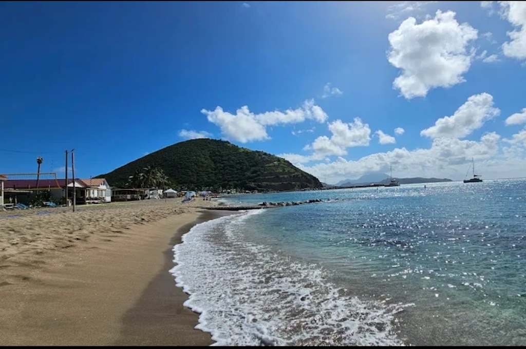 strand Karibikstrand mit türkisfarbenem Wasser und grünem Hügel