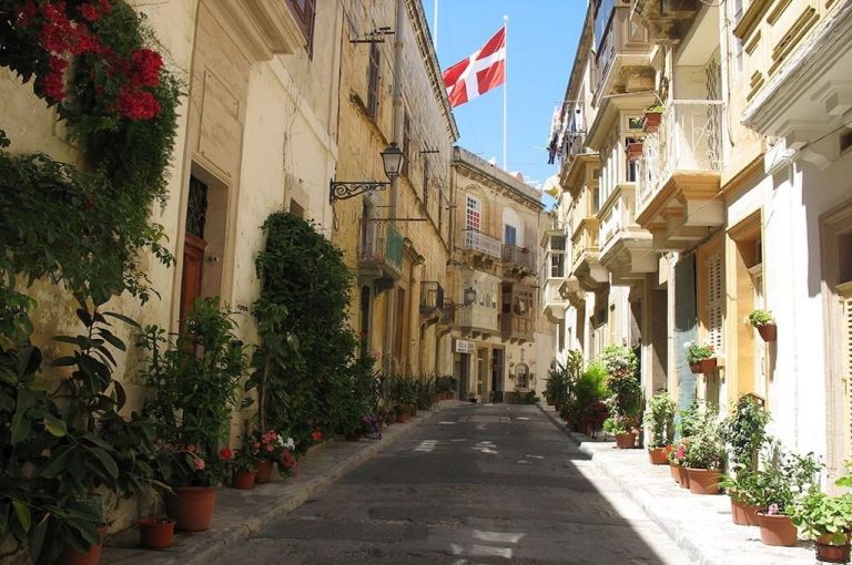 Enge Altstadtgasse mit Blumen und Flaggen auf Malta