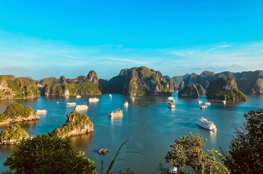 Blick von oben auf Ausflugsschiffe zwischen den Felsen der Halong-Bucht